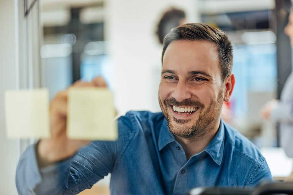 Mann schreibt auf Postit